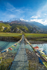 Suspension bridge with buddhist prayer flags on the Annapurna circuit trek in Nepal