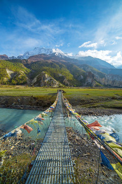Fototapeta Suspension bridge with buddhist prayer flags on the Annapurna circuit trek in Nepal