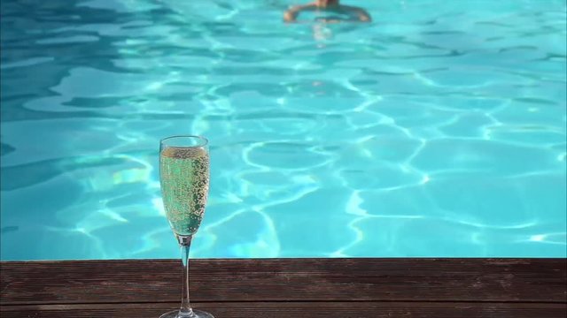 young happy woman drinks champagne in a swimming pool