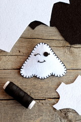 Cute Halloween ghost decor, felt sheets, black thread on an old wooden table. White ghost ornament made at home. Halloween children art diy. Sewing toy. Top view