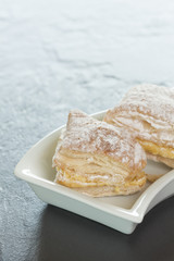 Puff pastry cake with cream and powdered sugar