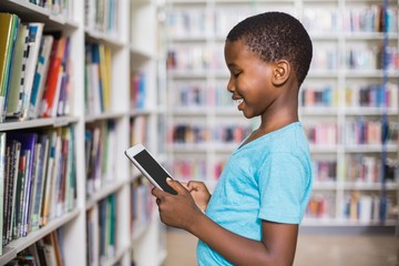 Schoolboy using digital tablet in library