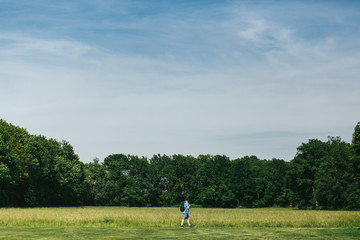 Man in blue shorts walk along the green lawn