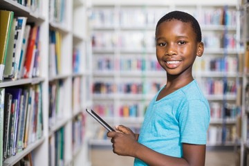 Schoolboy using digital tablet in library
