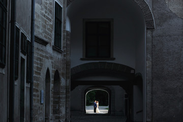 Hugging newlyweds stand in the end of a tunnel