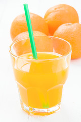 glass of juice and  oranges on table