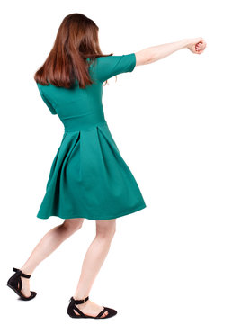 skinny woman funny fights waving his arms and legs. Isolated over white background. The slender brunette in a green short dress causes a sharp blow.