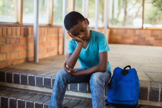 Sad Schoolboy Sitting Alone On Staircase