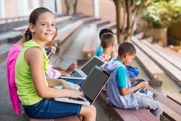 Kids sitting on bench and using laptop