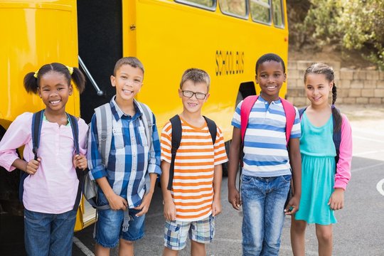 Smiling Kids Standing Together In Front Of School Bus