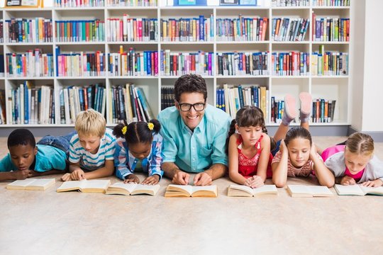 Teacher and kids reading book in library