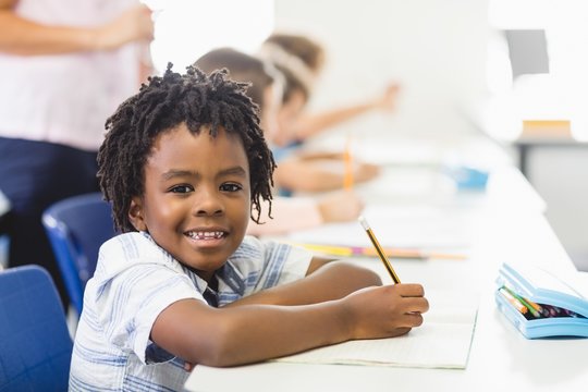 School boy doing homework in classroom