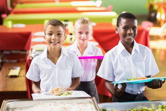 Student holding food tray in school cafeteria 