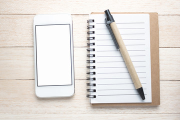 Smart phone, pen and notepad on wooden background close-up