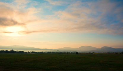 Misty sunrise and beautiful hills. Peaks of hills are sticking out from foggy background