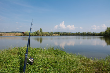 Fototapeta premium Carp fishing rod on the edge of a lake on a sunny summer day
