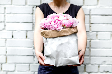 woman with bouquet of peonies in kraft bag