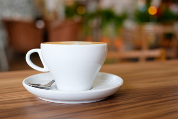 White mug cup containing hot coffee on wooden table