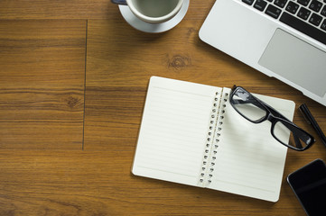 Office table with notepad, laptop and coffee cup.View from above with copy space.