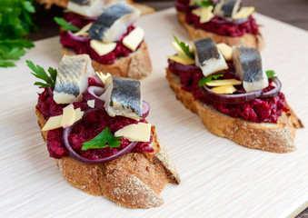 Meatless dietary sandwich: boiled beetroots, purple onion, salted herring and flakes of smoked cheese on a crispy baguette