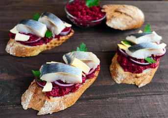 Meatless dietary sandwich: boiled beetroots, purple onion, salted herring and flakes of smoked cheese on a crispy baguette