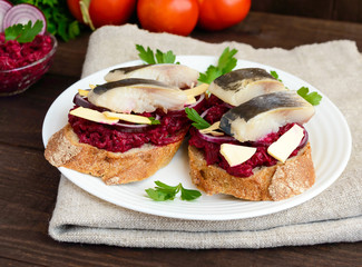 Meatless dietary sandwich: boiled beetroots, purple onion, salted herring and flakes of smoked cheese on a crispy baguette