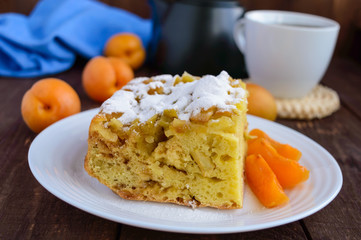 A piece of homemade cake with slices of apple and apricot, decorative powdered sugar.