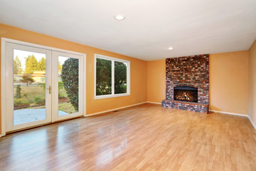 Empty living room with brick fireplace and hardwood floor