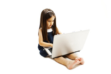 Fototapeta premium Adorable little girl is sitting on floor with her laptop. Isolated on white background 