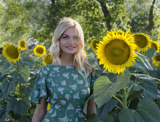 Smiling young woman on the field with sunflowers