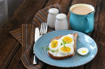 Sandwich with boiled egg and cream cheese. Milk coffee.