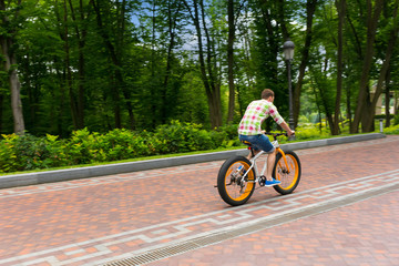 Obraz premium Male riding a bike on a footpath in a park