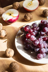 Apple, nuts and grape on wooden table in bright light
