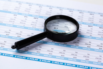 financial documents with magnifying glass over them