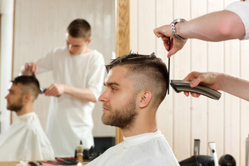 hairdresser cutting hair with hairclipper to his client