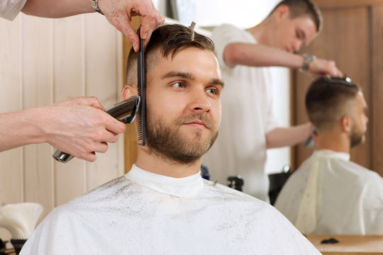 Young bearded man getting beard haircut by hairdresser