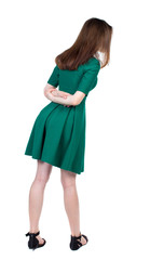 back view of standing young beautiful  woman.  girl  watching. Rear view people collection.  backside view of person. Slim brunette interest looking down in green short dress.  