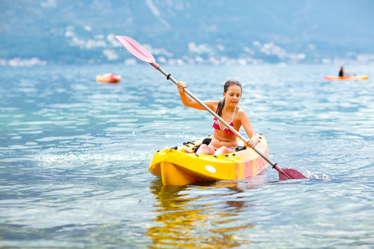 Girl enjoying paddling in kayak on the sea water 