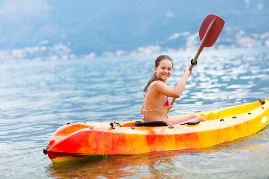 Girl enjoying paddling in kayak on the sea water 