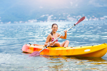 Girl enjoying paddling in kayak on the sea water 