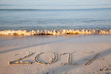Year and number 2017 written on the sand on a beach