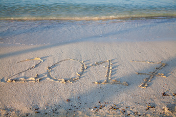 Year and number 2017 written on the sand on a beach