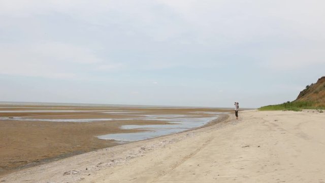 A man walks along the coast of the sea. There is no water, drought. Wind hot weather. Climate change, the draining of the seas. Ecological problems.