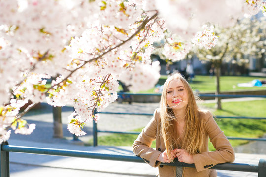 Sun shines over a pretty blonde posing in the blooming park