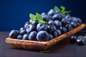 blueberries with green leaves in wooden dish