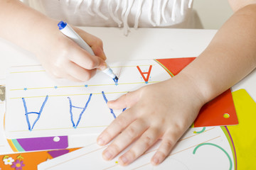 Little child hands writing letter A. Learning to write. Little girl writing alphabet in a copy book at a desk. Learn Study Education School Knowledge Concept