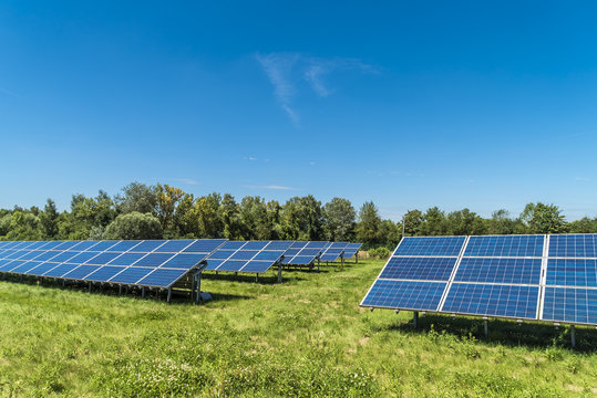 Blaue Solarmodule in gr&uuml;ner Natur sorgen f&uuml;r Energiewende