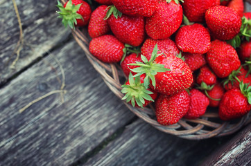 Strawberry in wicker plate on wooden background