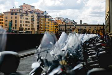 Naklejka premium Scooters and motorcycles stand in the ray along the stone bridge