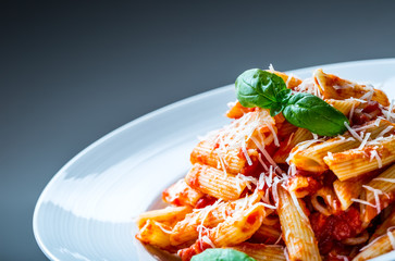 Pasta Penne with Tomato Bolognese Sauce, Parmesan Cheese and Basil Leaves. Mediterranean food.Italian cuisine.
